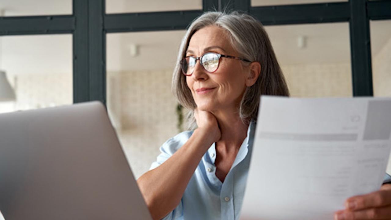 happy middle aged business woman using laptop at desk