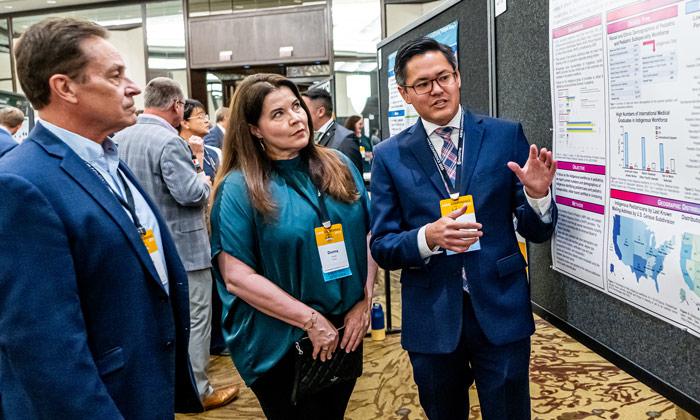 ABMS Scholar discusses poster with attendees at ABMS Conference