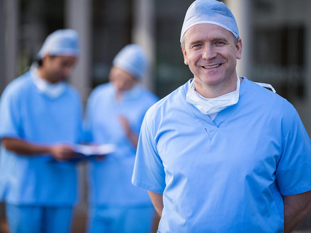 standing male doctor with doctors in background